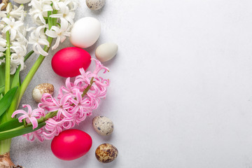 Obraz na płótnie Canvas Bright Easter composition with quail, easter eggs, pink and white hyacinth on stone background. Flat lay, top view. Easter concept
