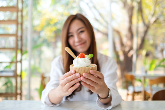 Closeup image of a beautiful asian woman showing and eating an ice cream in restaurant