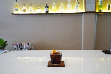 Close up glass of iced black coffee with orange on wooden tray