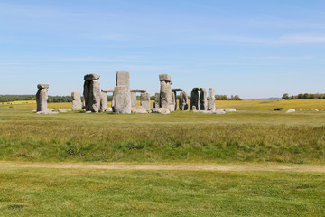 View of Stonehenge with green meadow and blue sky on a sunny day in Spring, United Kingdom