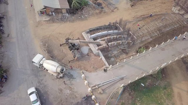 Aerial static view of a crane used to carry an empty bucket from  the new bridge to the cement mixer truck for pouring concrete into a bucket