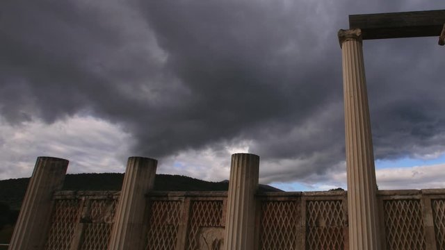 Time lapse of dark clouds moving and sunlight shining on the ancient pillars of the Asclepeion temple of Epidaurus in Greece