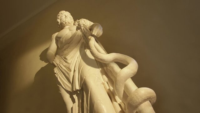 Animated statue of  god Asclepius, snake entwined on rod