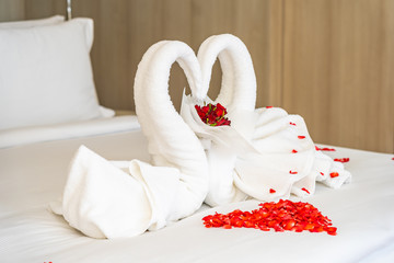 Swan towel on bed with red rose flower decoration interior