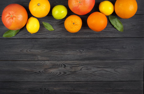 Citrus fruits: Lemon, Grayfruit, Mandarin, Orange, Lime on a dark gray wooden background. Top view