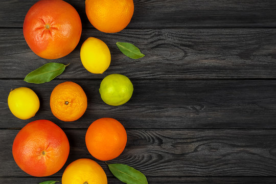 Citrus fruits: Lemon, Grayfruit, Mandarin, Orange, Lime on a dark gray wooden background. Top view