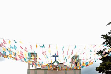 Upper facade of Christian church with Mexican bell towers and pennants.