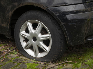 Fototapeta na wymiar flat tire of an abandoned damaged old black car