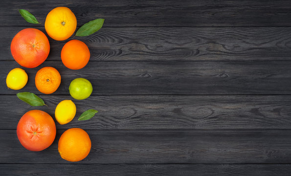 Citrus fruits: Lemon, Grayfruit, Mandarin, Orange, Lime on a dark gray wooden background. Top view