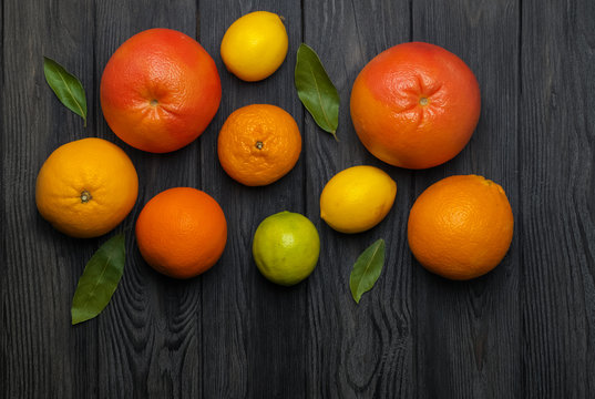 Citrus fruits: Lemon, Grayfruit, Mandarin, Orange, Lime on a dark gray wooden background. Top view