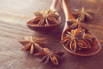 Anise stars in a wooden spoon on a wooden table. Close-up. Food concept