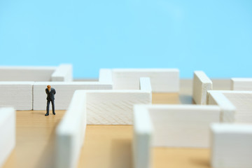 Business strategy conceptual photo - Miniature of businessman looking for solution on a labyrinth maze