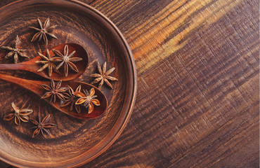 Anise stars in wooden spoons on a clay plate. Top view. Food concept.