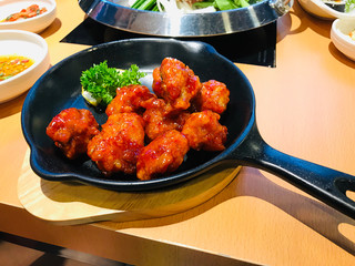 Fried chicken mixed with Korean style sauce served in frying pan. 