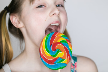 Fototapeta na wymiar Young girl licking colorful lollipop