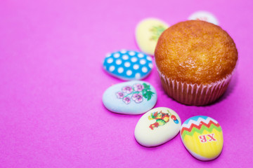 on a pink background close-up of colored Easter eggs and cupcake, holiday background