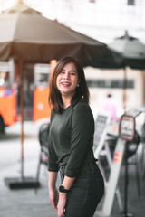 Fototapeta premium Portrait of Smart Asian Woman Smiling in Front of Coffee Shop at Co-Working Space in Shopping Center on Business District Location - Happy Emotion Relax Concept (Vintage Film Tone)
