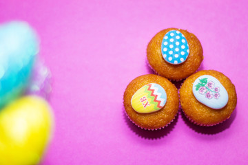 on a pink background close-up of colored Easter eggs and cupcake, holiday background