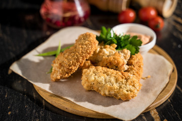 chicken nuggets in batter, serving nuggets on a wooden plank with cream sauce, serving a meal in a restaurant, serving a meal in a bar