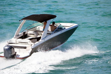Angled view of a motor boat with black canvas canopy and one outboard engine.