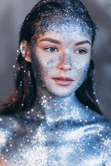 Close up portrait of young fashionable model with art make up with blue sparkles. Fashion, art, beauty concept
