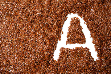 background with texture made of of brown flax seeds with a white letter of vitamin A