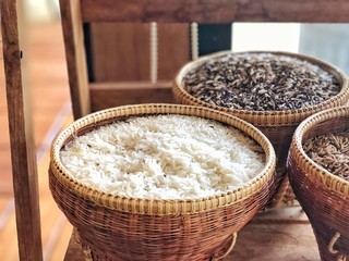Jasmine rice and rice berry rice in the bamboo baskets, local objects style, Thailand agriculture products. light color mode design. Selective focus and blur background.