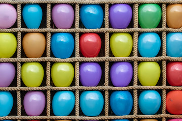 Many colorful balloons in square cages for playing darts. Colorful background, rainbow colors. Close-up. Entertainment.