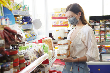  Woman wearing protective mask while grocery shopping in supermarket, Coronavirus contagion fears concept	