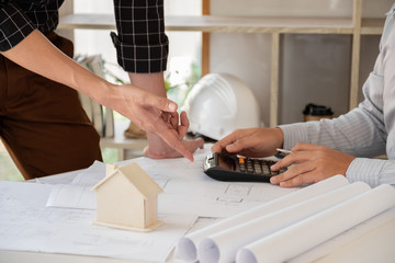 A team of confident architects working together in the office talking about construction and home design projects. House design ideas
