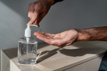 Hand sanitizer bottle man using dispenser gel rub for corona virus hands hygiene coronavirus COVID-19 pandemic prevention.