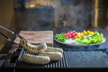 A cook turns over tongs of chicken to a grilled
