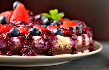 Cheesecake with fresh strawberries, blueberries and cherry jam. Low depth of field