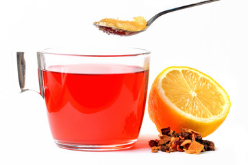 Cup of fruit tea, half pieced lemon, heap of dried tea and teaspoon of honey isolated on white background.
