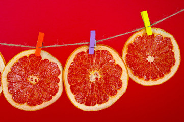 Chips of dried grapefruit sliced in thin circles, shot on a red background. Background for vegetarianism, healthy and wholesome food.