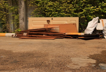 Discarded damaged door and stack of worn out plywoods are threw away in front of dump site, waiting for recycle process 