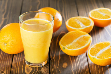 Orange juice glass and fruits on wooden table.