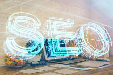 Double exposure of table with computer and seo drawing hologram. Search optimization concept.