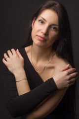 portrait of a brunette on a dark gray studio background in a black dress