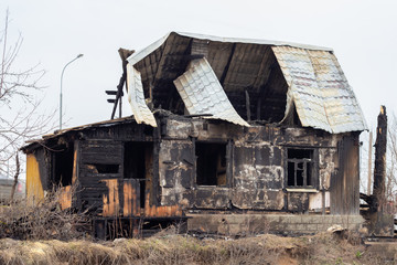 A sinful house, arson incident. Broken roof and glass windows, charred walls. Arson of a one-story private house, property insurance against fire