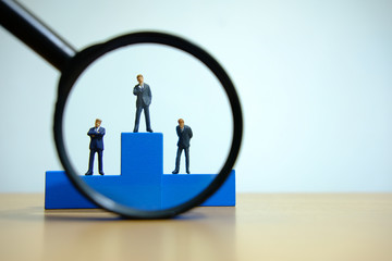 Business conceptual photo – miniature of businessman stands on wooden podium