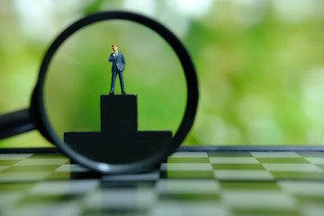 Business conceptual photo – miniature of businessman stands on wooden podium