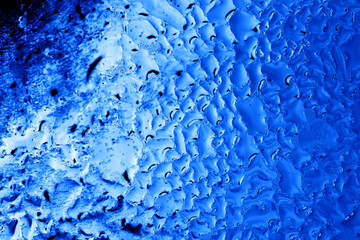 Blue drops of water on glass as an abstract background