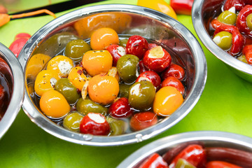Green, yellow and red peppers piled in metal plates. Assorted vegetables, vegetables with spices in oil.