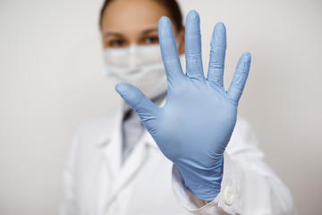 a female infectious disease doctor in a protective mask and medical gloves on a white background, held out her hand in front of her