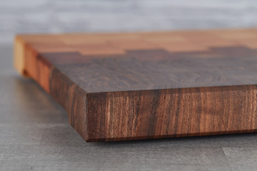 Beautiful cutting Board made of different types of wood with a geometric pattern lies on the table. Serve the dishes.