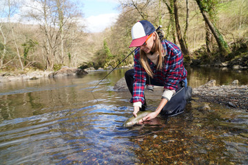 woman catching rainbow trout fly in river