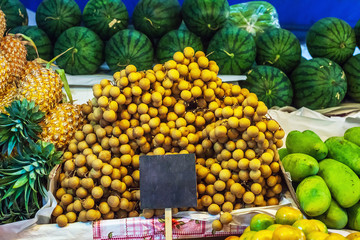 Sweet tropical fruits Dimocarpus longan bunches and pineapples sale at market