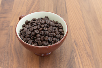 Dark roasted coffee beans in a cup.