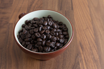 Dark roasted coffee beans in a cup.